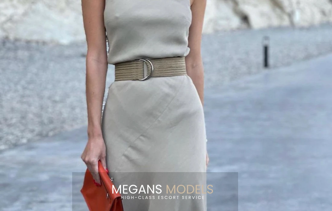 An escort standing in a grey dress
